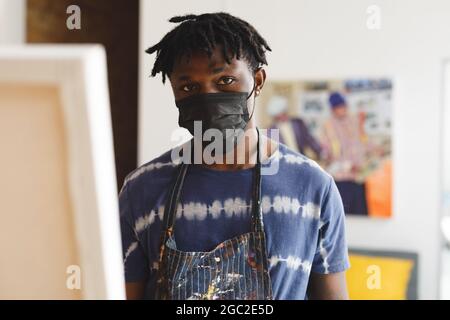 Ritratto di pittore africano americano maschile indossando maschera facciale in studio d'arte Foto Stock