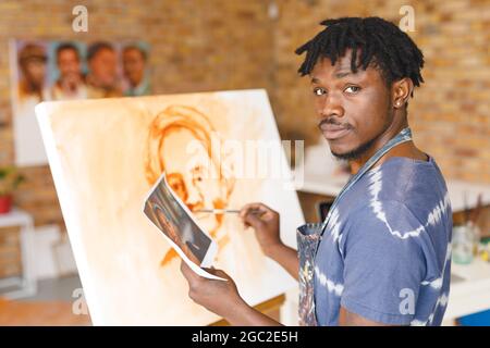 Ritratto di pittore maschile afroamericano al lavoro pittura ritratto su tela in studio d'arte Foto Stock