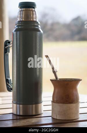 Closeup verticale di una tazza di infuso di yerba mate con un thermos. Foto Stock