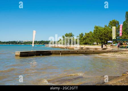 Porec, Croazia - 10 luglio 2021. Un molo a Parentino Beach fuori dalla storica cittadina costiera medievale di Porec in Istria, Croazia Foto Stock