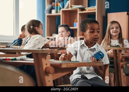 Premuroso bambino con il suo giocattolo preferito a scuola Foto Stock