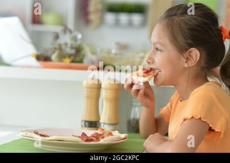 Bambina che mangia gustosa pizza a casa Foto Stock