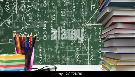 Articoli fissi della scuola e vetri contro equazioni matematiche galleggianti su sfondo verde Foto Stock