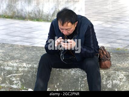 Un uomo che verifica il suo cellulare dal lato della strada a Greenwich, Londra del sud. © Foto di Richard Walker Foto Stock