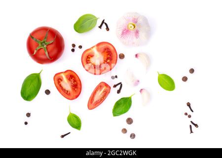 vista dall'alto della ​​tomato intera e tagliata a fette con foglie di basilico e aglio, spezie, isolato su sfondo bianco Foto Stock