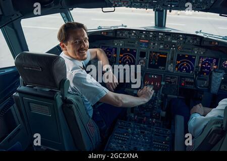 Gioioso pilota capo in posa per la telecamera nel cockpit Foto Stock