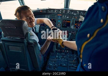 Il capitano della compagnia aerea è servito caffè nell'abitacolo Foto Stock