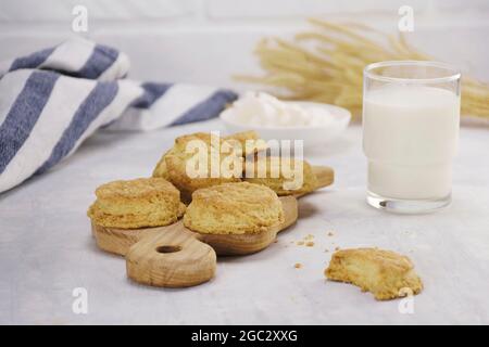 Biscotti su tavola di legno con un bicchiere di latte su un tavolo leggero, cucina Foto Stock
