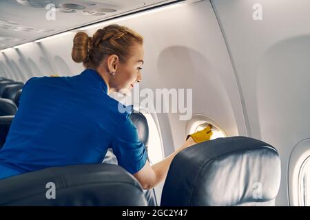 Sorridente padrona d'aria che chiude l'ombra della finestra Foto Stock