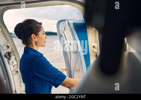 Giovane stewardess in piedi nella porta dell'aereo Foto Stock