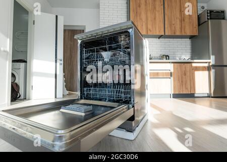 Macchina lavastoviglie integrata aperta in una cucina moderna Foto Stock