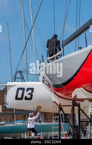 settimana dei cowes, manutenzione degli yacht, equipaggi di yacht, cowes yacht haven, isola di wight, equipaggio che lavora su yacht da corsa, regata di vela, regata di yacht. Foto Stock