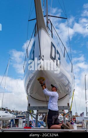 settimana dei cowes, isola di wight, barca di lucidatura uomo, barca di pulizia membro dell'equipaggio, scafo lucidante di yacht da corsa, manutenzione di regate di vela, equipaggio di yacht. Foto Stock