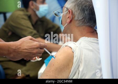 (210806) -- TEL AVIV, 6 agosto 2021 (Xinhua) -- un uomo israeliano riceve una terza vaccinazione contro COVID-19 nella città centrale israeliana di Tel Aviv il 6 agosto 2021. Finora, il numero di persone che hanno ricevuto la prima dose di vaccino in Israele ha raggiunto quasi 5.8 milioni, ovvero il 62.2% della sua popolazione totale, mentre quasi 5.39 milioni sono stati vaccinati con la seconda dose, e più di 295,000 con la terza dose. (Gideon Markowicz/JINI via Xinhua) Foto Stock