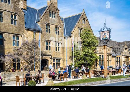 La gente gode del sole primaverile, fuori da un pub nella città di Cotswold di Broadway nel Worcestershire. Foto Stock