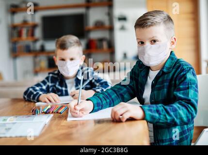 bambino ragazzo compiti schold istruzione classe studiare infanzia maschera protezione virus corona casa Foto Stock
