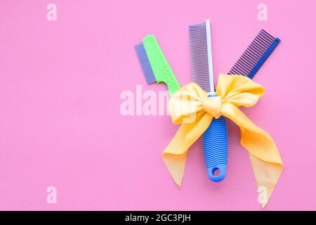 Set di pettini legati con un arco giallo e parrucchieri per la cura del corpo su sfondo rosa. Vista dall'alto, layout, spazio di copia. Foto Stock