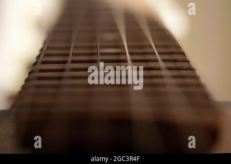 Dettaglio closeup di corde di chitarra in acciaio e tasti per fare musica. Fuoco selettivo su una soglia di chitarra. Foto Stock