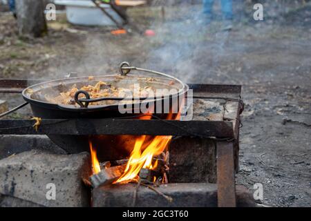 Cucinare carne con verdure in un grande calderone, cibo di strada all'aperto. Foto Stock