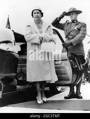 Royal Tour of Canada H.M la regina è salutata da un Mountie, un ufficiale Royal Canadian Mounted Police, come lei tiene aperta la porta dell'auto al suo arrivo all'aeroporto di Gander a Terranova, Canada, per aprire ufficialmente un nuovo edificio del terminal. 19 giugno 1959 Foto Stock