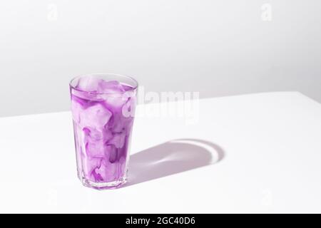 Caffè ghiacciato, bevanda alla lavanda su sfondo bianco. Latte di miele viola lavanda. Foto Stock