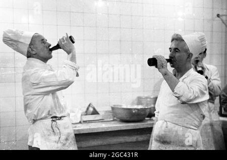 Dietro le quinte in un banchetto di stato. Banchetto di ritorno per la Regina Elisabetta II alla Mansion House, Londra dopo il suo Commonwealth Tour nel 1954. La società di catering di Ring & Brymer (Birch’s) Ltd ha gestito il catering in ogni banchetto di coronazione dato dalla Corporation of London sin dall’incoronazione della Regina Victoria e ha prestato servizio per più teste coronate di qualsiasi altra azienda al mondo. 19 Maggio 1954 Mostre fotografiche: Due cuochi d'assistente prendono la loro birra dalla bottiglia. Foto Stock