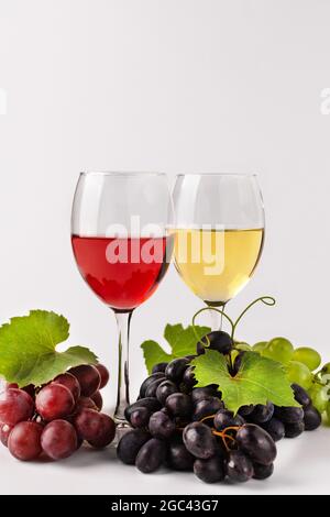 Composizione del vino con bicchieri e uva. Bicchieri di vino rosso e bianco e varietà di uva su sfondo bianco. Foto Stock