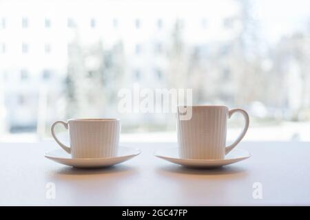 Soglia della finestra dell'ufficio, caffè con vista sulla città e due tazze con tè o caffè tazze nella prima colazione del mattino Foto Stock