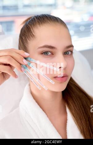 Bellezza estetica anti invecchiamento, lifting chirurgia viso per grazioso cliente, vista laterale close-up. Beautician professionale che fa procedura di scelta degli stanziamenti Foto Stock