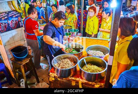 LAMPANG, THAILANDIA - 8 MAGGIO 2019: Caotica coda di persone di fronte al bancone della bancarella di cibo, che offre una grande quantità di piatti da asporto di cucina tailandese Foto Stock