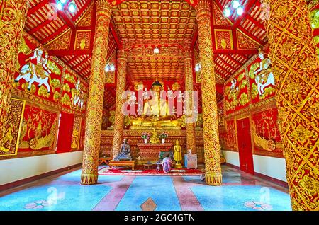 LAMPANG, THAILANDIA - 8 MAGGIO 2019: Interno del viharn di Wat Phrao con l'immagine del Buddha di si Sakyamuni sull'altare, numerose sculture murali, patte in rilievo dorato Foto Stock