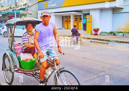 LAMHPUN, THAILANDIA - 8 MAGGIO 2019: Il ritratto di sorridente alto trishaw, in sella al suo taxi a tre ruote, l'8 maggio a Lamphun Foto Stock