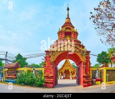 La bella porta rossa del Tempio di Wat Sangkharam è decorata con stampaggio in rilievo dorato, sculture di serpenti Naga, immagine Buddh e sormontata con piccolo Foto Stock