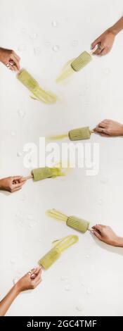 Le mani delle donne prendono i popsicles di cocco di matcha di fusione dal tavolo Foto Stock