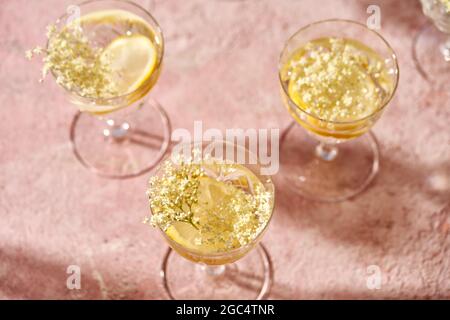 Bicchieri di limonata estiva con fiori neri di ontano freschi su sfondo rosa Foto Stock