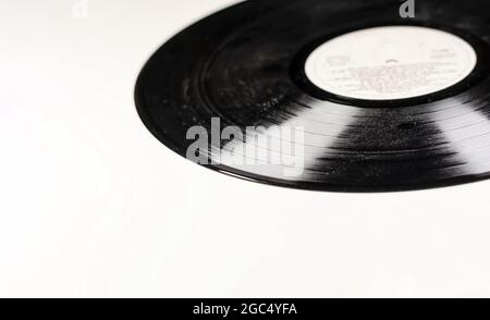 un vecchio disco in vinile nero polveroso isolato su sfondo bianco. Apparecchiature per l'ascolto di musica. Oggetto vintage Foto Stock