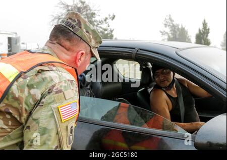 Oregon Army National Guard staff Sgt. Randy Bowman, quartier generale e quartier generale Troop, 1° Squadron, 82° reggimento Cavalleria, parla con un residente locale che entra nel suo quartiere dove Bowman mans un punto di controllo del traffico (TCP) per aiutare a mantenere il quartiere e la comunità al sicuro, Warm Springs, Ore., 17 settembre 2020. Il fuoco di Lionshead, situato a 14 miglia ad ovest di Warm Springs, potrebbe potenzialmente condurre ad un'evacuazione, lasciando le case vulnerabili. Bowman, situato in uno dei quattro TCPS lungo l'autostrada US 26, aiuta a rassicurare i cittadini locali e controlla chiunque entri ed esca dai quartieri, costruendo Foto Stock