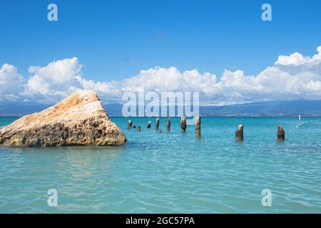 Una grande roccia triangolare e i resti di un vecchio molo nelle acque turchesi al largo di Isla de Cajo de Muertos, Puerto Rico, USA. Foto Stock