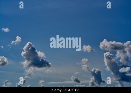 Sole che splende in un cielo blu e bianco. Cielo blu profondo con nuvole e raggi solari. Foto Stock