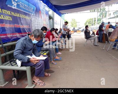 Editoriale Photo, Indonesia, East Jakarta, Samsat Office, 06 agosto 2021, Persone che siedono vicino a Bus Samsat Keliling, STNK, Yearly Tax, One Stop Administrir Foto Stock