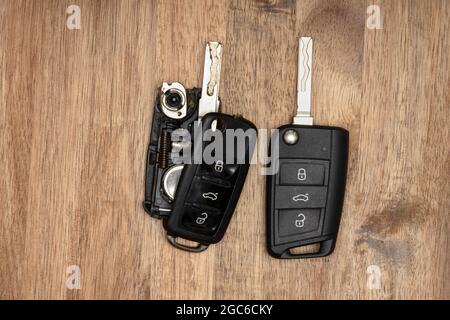 Portachiavi auto rotto o danneggiato su sfondo in legno. Riparazione di un'auto officina con telecomando rotta o danneggiata. Foto Stock