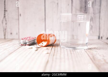 pillola medica, confezione blister e bicchiere d'acqua sul tavolo Foto Stock