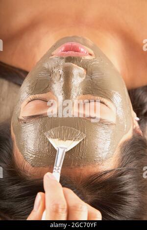 Donna con maschera di fango e di cetrioli sul viso Foto Stock