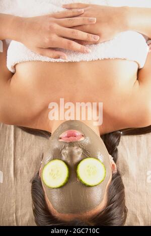 Donna con maschera di fango e di cetrioli sul viso Foto Stock
