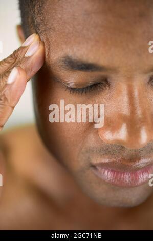 Primo piano delle tempie di sfregamento dell'uomo Foto Stock