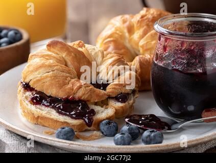 Primo piano di croissant, mirtilli e marmellata di mirtilli su un piatto Foto Stock