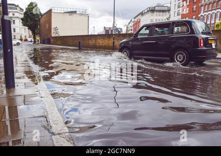 Londra, Regno Unito. 7 agosto 2021. Un taxi londinese si tuffa in un vicolo di Farringdon allagato dopo una giornata di forti piogge nella capitale (Credit: Vuk Valcic / Alamy Live News) Foto Stock