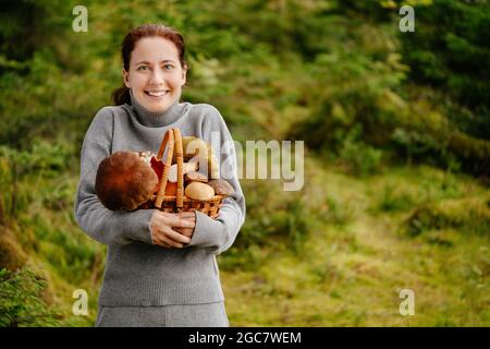 La giovane donna ha raccolto molti funghi nella foresta Foto Stock