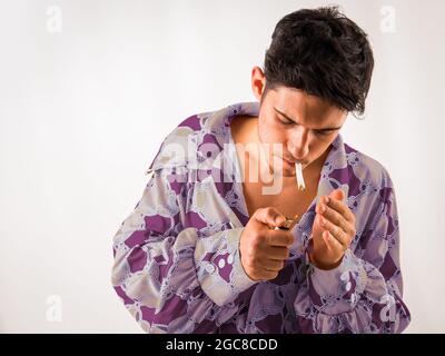 Giovane uomo fumante sigaretta, con abiti hippie Foto Stock