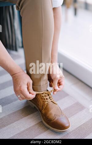 Lo sposo stringe i lacci sulle brogues marroni. Primo piano Foto Stock